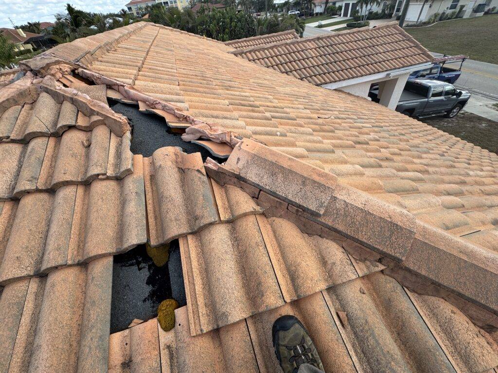 Damaged concrete tile roof with slipped tiles and exposed underlayment