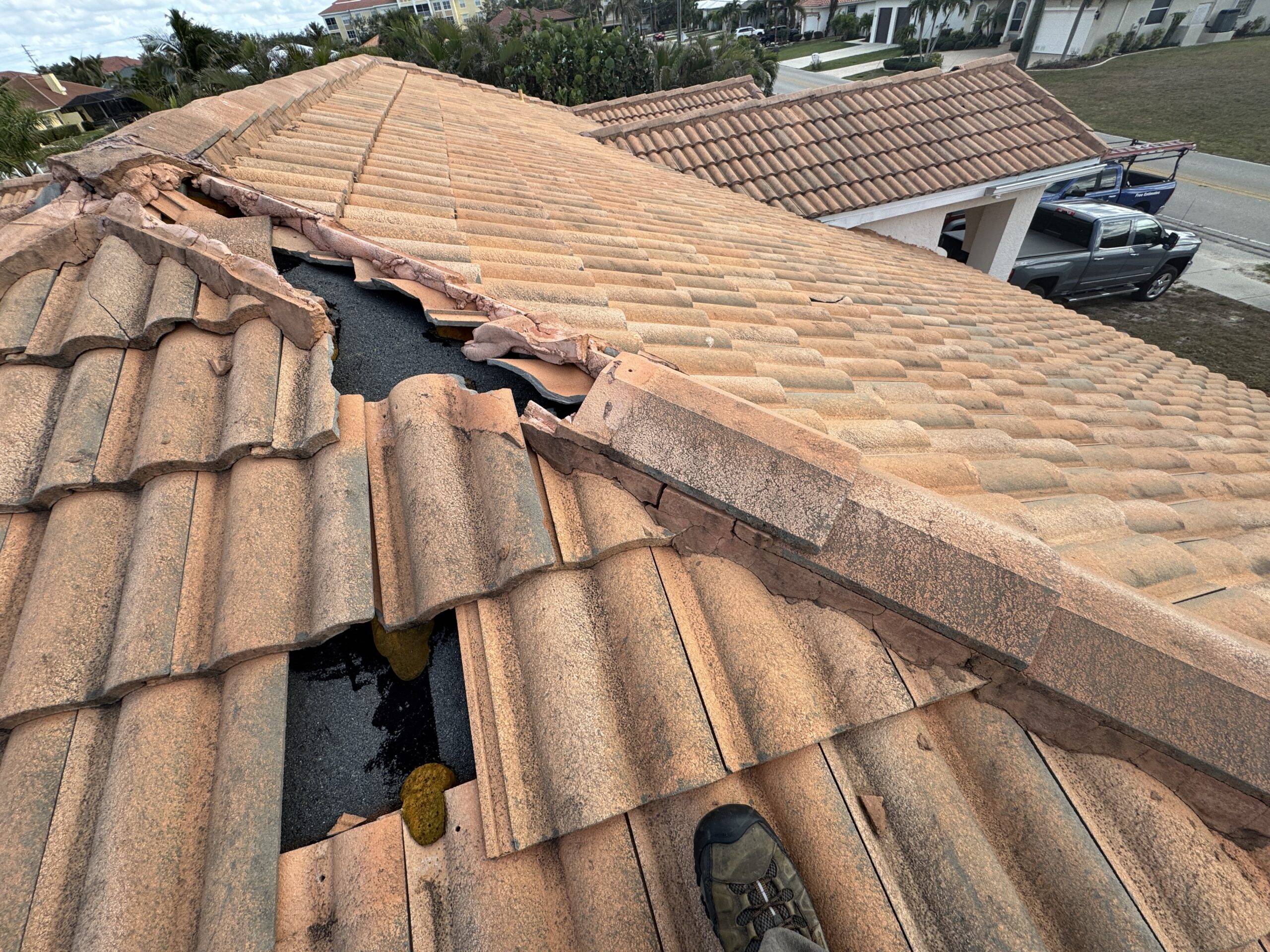 Damaged concrete tile roof with slipped tiles and exposed underlayment